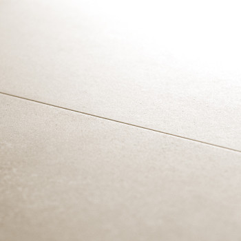 Un carreau lisse et beige repose horizontalement, traversé par une fine ligne de coulis dans un décor intérieur doucement éclair