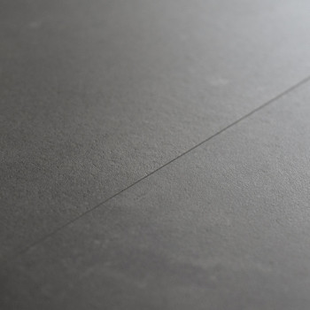 Un carreau lisse et gris foncé repose à plat, avec une couture légèrement visible en diagonale, suggérant un espace intérieur ca