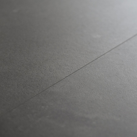 Un carreau lisse et gris foncé repose à plat, avec une couture légèrement visible en diagonale, suggérant un espace intérieur ca