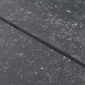 Eine strukturierte graue Fliese weist subtile Sprenkel auf und erzeugt ein steinähnliches Aussehen, eingebettet in eine glatte, 