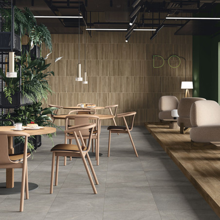 Mesas e cadeiras de madeira ficam sobre um piso de cerâmica cinza claro em um café moderno com vegetação e iluminação minimalist