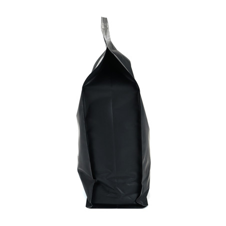 Un sac noir scellé se tient debout, sans marque, sur un fond blanc uni, suggérant un produit emballé.