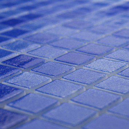Blaue Glasfliesen bilden ein strukturiertes Mosaikmuster und schaffen eine schimmernde Oberfläche in einem sanft beleuchteten Ra