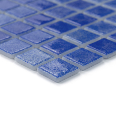 Blaue Glasfliesen bilden auf einer glatten Oberfläche ein Gittermuster, das das Licht subtil reflektiert.