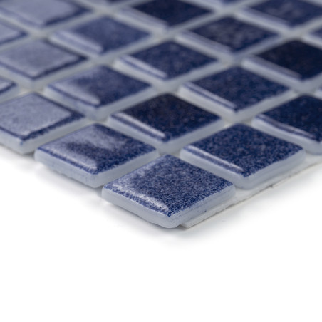 Los azulejos de vidrio azul colocados uniformemente, reflejando la luz, forman un elegante patrón de mosaico sobre una superfici