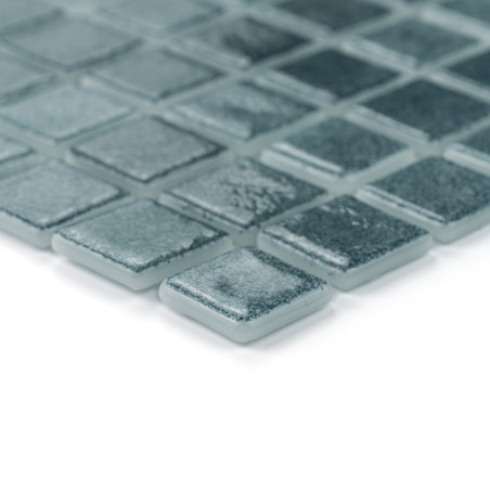 Vierkante glastegels netjes gerangschikt, licht subtiel reflecterend, in een rasterpatroon tegen een egale witte achtergrond.