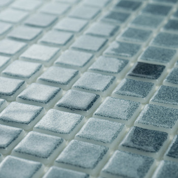 Glasmosaikfliesen zeigen unterschiedliche Blautöne und erzeugen im Umgebungslicht einen schimmernden Effekt auf einer ebenen, gl