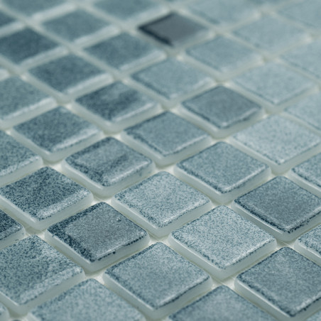 Quadratische Glasfliesen schimmern dezent und reflektieren das Licht über ein Gitter, wodurch ein strukturiertes, gleichmäßiges 