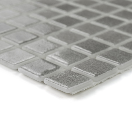 Square glass tiles form a shimmering silver mosaic, reflecting light, arranged in a grid pattern against a soft surface.