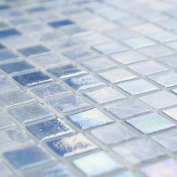 Mosaicos de vidro iridescentes brilham em uma superfície, exibindo vários tons de azul e branco em um padrão de grade.