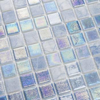 Los azulejos de vidrio iridiscente brillan y reflejan la luz multicolor en medio de una cuadrícula de cuadrados mate que parecen