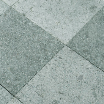 Grijze steentegels vormen een geruit patroon, afwisselende tinten, waardoor een gestructureerd, industrieel vloeroppervlak ontst