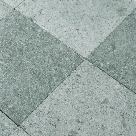 Les carreaux de pierre grise forment un motif en damier, alternant les nuances, créant une surface de sol texturée et industriel