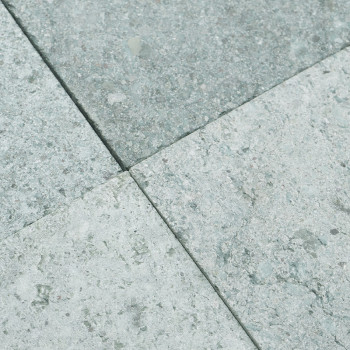 Ladrilhos de pedra cinza dispostos em uma grade ficam uniformemente no chão, formando uma superfície texturizada e uniforme.