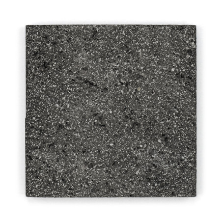 Carreau de pierre carré présentant une surface mouchetée et texturée. reposant à plat sur un fond blanc.