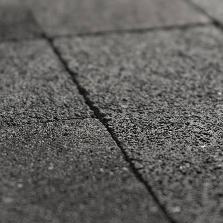 Ladrilhos de pedra cinza formam um padrão de grade, exibindo uma textura áspera, perfeitamente alinhados em um ambiente externo.