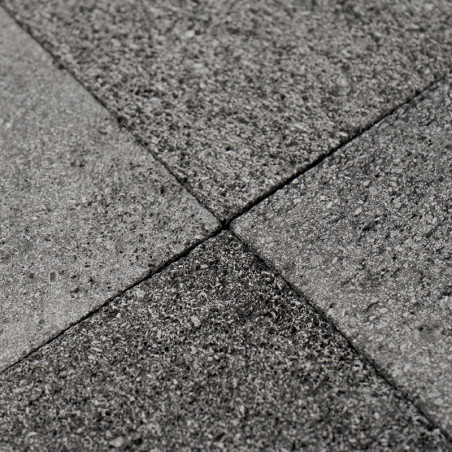 Los azulejos de piedra gris forman un patrón texturizado entrelazado sobre una superficie plana, creando un piso uniforme y dura