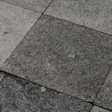 Los azulejos de piedra gris forman una superficie texturizada e irregular con un patrón geométrico, que transmite una estética r