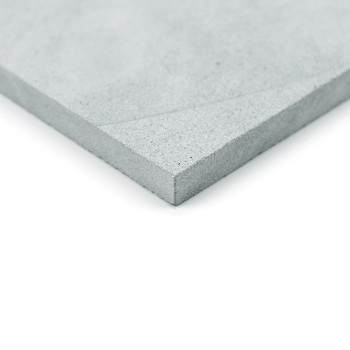 Grijze steentegel, plat liggend, met een gestructureerde hoek. gefotografeerd tegen een witte achtergrond.