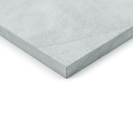 Grijze steentegel, plat liggend, met een gestructureerde hoek. gefotografeerd tegen een witte achtergrond.