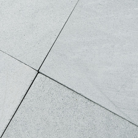 Les carreaux de pierre grise se croisent harmonieusement, formant un motif de grille épuré, suggérant un revêtement de sol extér