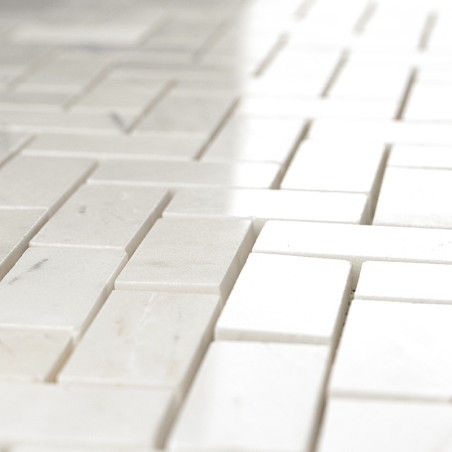 White rectangular stone tiles, arranged in a staggered pattern, reflect light in a smooth, uniform surface.