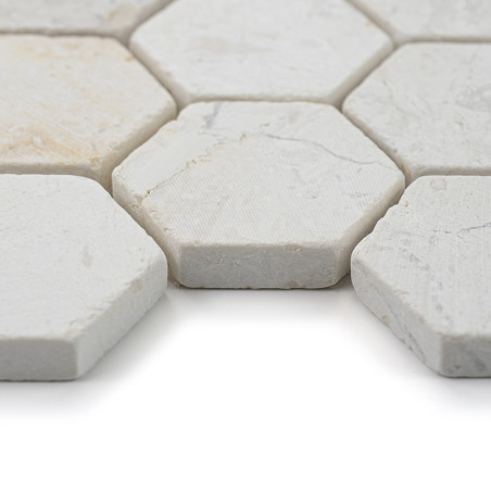 Les carreaux de pierre hexagonaux sont étroitement alignés, affichant une surface texturée blanc cassé dans un espace lumineux e