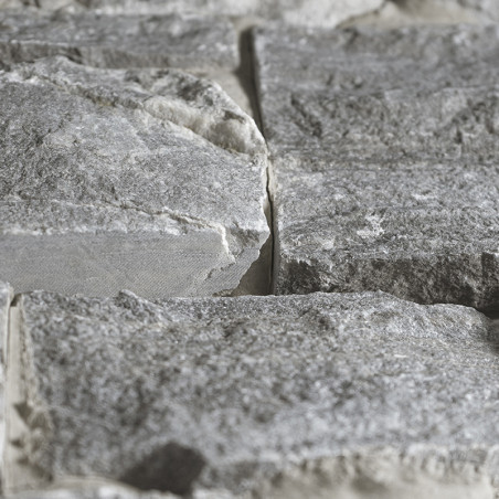 Graue Steinfliesen, die nebeneinander angeordnet sind und eine strukturierte Oberfläche in einer natürlichen, rauen Umgebung bil