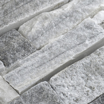 Ladrilhos de pedra de textura áspera ficam em um arranjo escalonado, criando uma superfície natural e irregular em um ambiente n