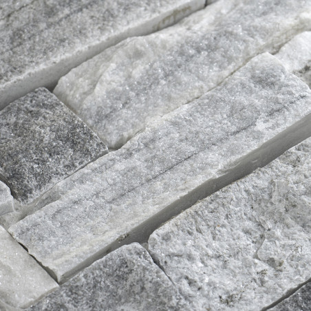 Des carreaux de pierre rectangulaires sont assemblés, mettant en valeur des textures brutes et variées et des nuances de gris, c