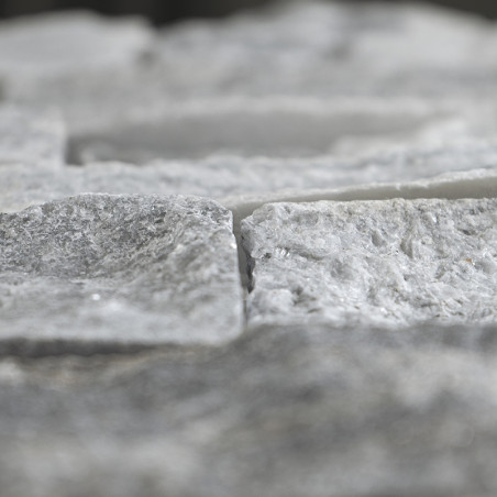 Steinfliesen mit grober Struktur liegen versetzt angeordnet und schaffen so eine natürliche, unebene Oberfläche in neutraler Umg