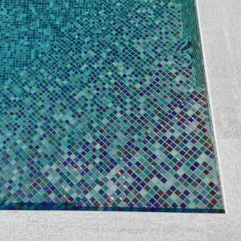 Blauwe en groene mozaïektegels creëren een ingewikkeld patroon langs de bodem van een rechthoekig zwembad.