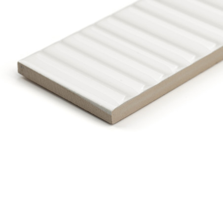 Un azulejo cerámico rectangular muestra una superficie blanca brillante y acanalada. se apoya sobre una base beige, aislada sobr