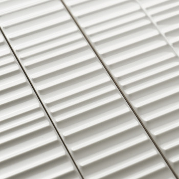 Weiße Keramikfliesen weisen erhabene lineare Rippen auf, die parallel angeordnet sind und ein strukturiertes Muster erzeugen. Si