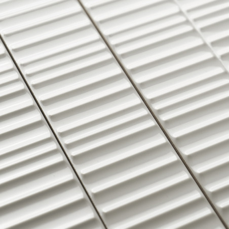 Los azulejos de cerámica blanca presentan crestas lineales elevadas, dispuestas en paralelo, creando un patrón texturizado. Está