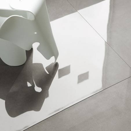 Um objeto de plástico branco em forma de elefante projeta uma sombra em pisos cinza claro e brilhantes, refletindo luz e formas 