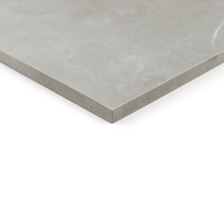 Un carreau de céramique lisse et gris repose sur une surface blanche, mettant en valeur son bord net et angulaire, suggérant un 