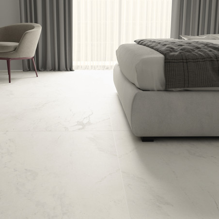 Een witte marmerachtige vloer strekt zich uit over een moderne slaapkamer, voorzien van een stoel en bed met kussens, en grijze 