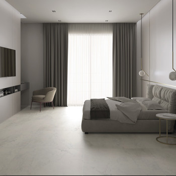 Een moderne slaapkamer is voorzien van een laag, gestoffeerd bed in de buurt van kamerhoge gordijnen. Een minimalistische stoel 