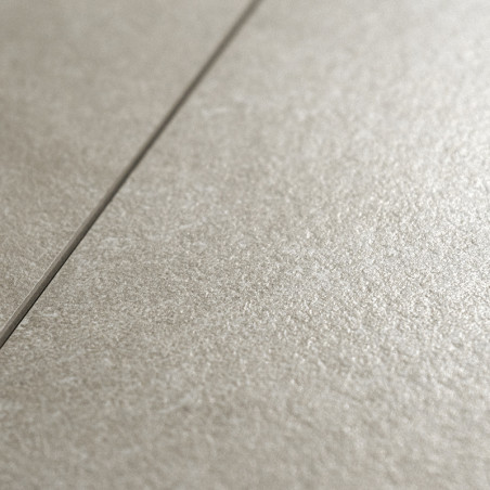 A textured, matte ceramic tile sits in close-up view, showcasing its subtle, light gray surface. A visible grout line divides th