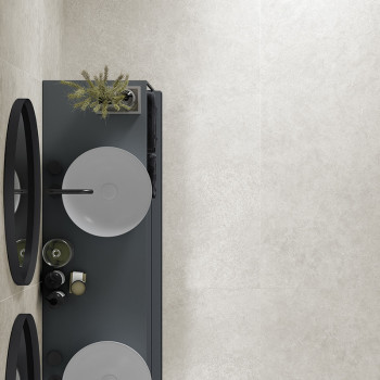 A sleek, rectangular bathroom counter holds two circular sinks with modern faucets. Above, mirrors are placed. the wall features