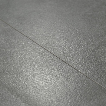 Le carrelage de sol texturé gris, présentant un éclat subtil, repose à plat. Une étroite ligne de coulis divise les carreaux, su