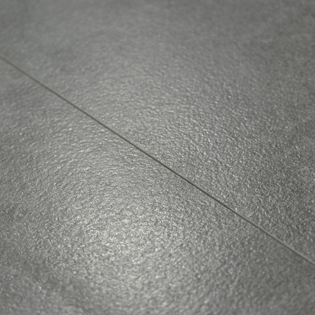 O piso com textura cinza, mostrando um brilho sutil, fica plano. Uma linha estreita de argamassa divide os ladrilhos, sugerindo 