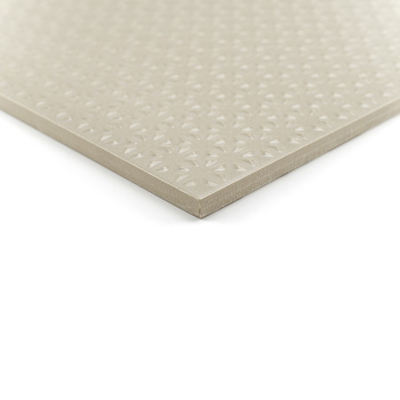 Un azulejo cuadrado de color beige descansa sobre un fondo blanco y muestra un patrón geométrico en relieve en su superficie lis