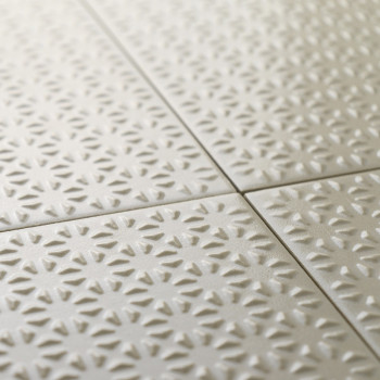 Les carreaux de céramique texturés forment un motif répétitif de formes rayonnantes de soleil dans une couleur beige douce, soig