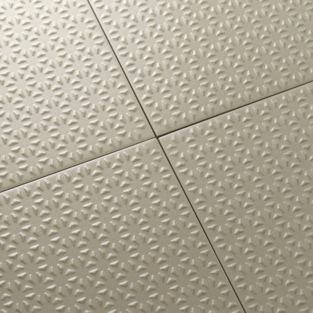 Los azulejos beige muestran un patrón continuo en relieve similar a una estrella, cuidadosamente alineados en una formación de c