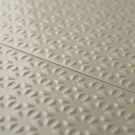 Los azulejos beige presentan un patrón floral en relieve que se repite, creando textura y profundidad. Los azulejos se alinean e