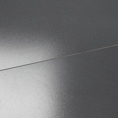 Un carreau gris foncé lisse et brillant reflète la lumière de manière subtile. Il est plat, divisé par une ligne de coulis droit