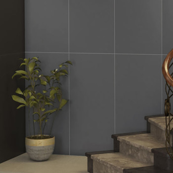 Une plante en pot se dresse contre un coin carrelé sombre à côté d’un escalier en béton, mettant en valeur l’espace intérieur mi