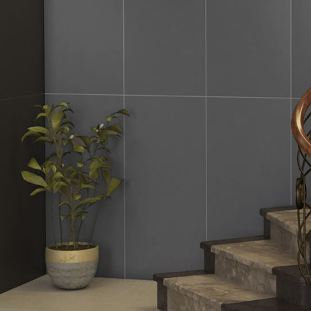 Une plante en pot se dresse contre un coin carrelé sombre à côté d’un escalier en béton, mettant en valeur l’espace intérieur mi